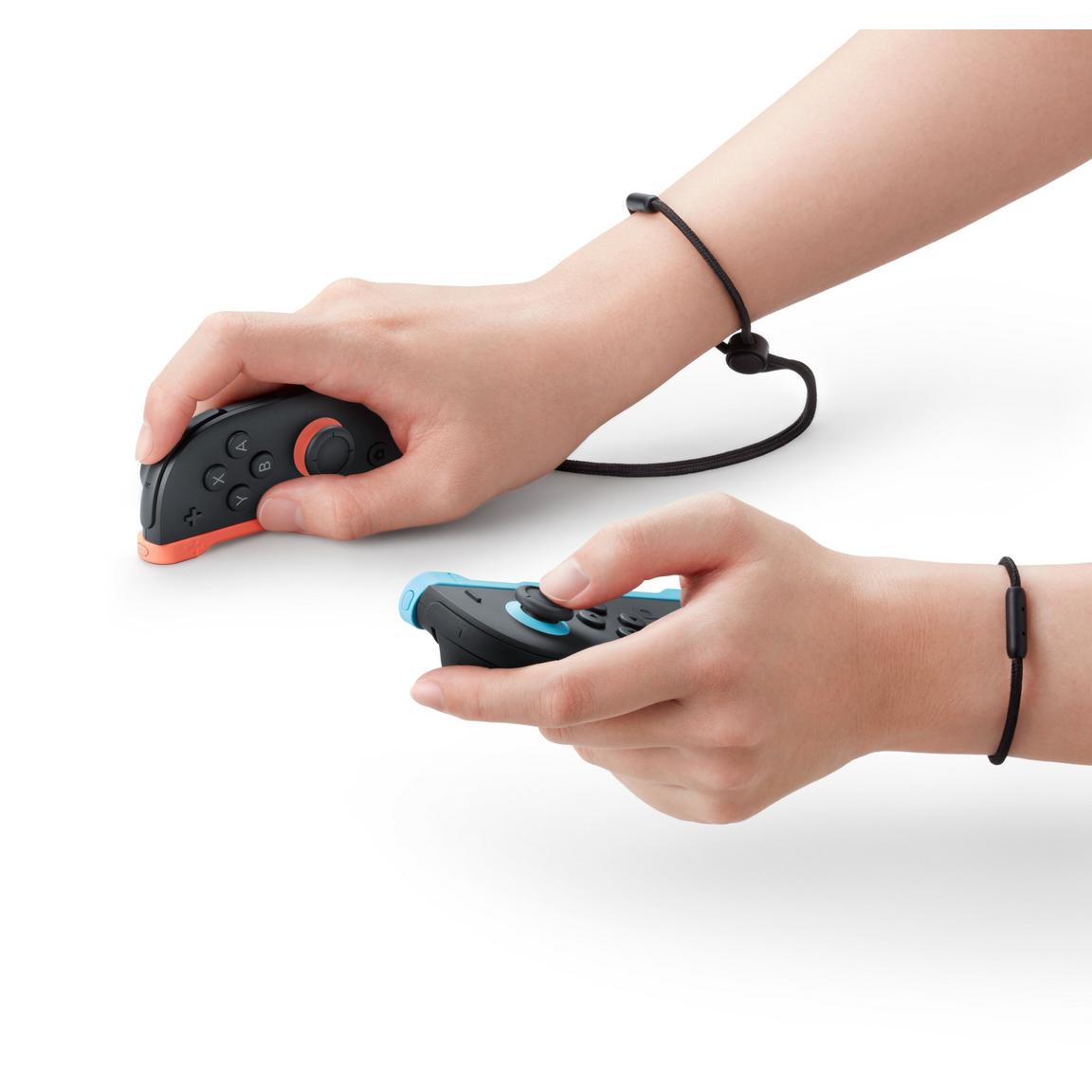 "Close-up view of hands holding the Nintendo Switch 2 Joy-Con 2 (L)/(R) Light Blue/Light Red, highlighting the ergonomic design and wrist straps for comfortable gaming."